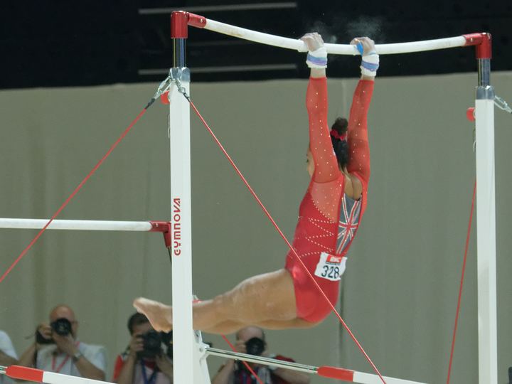 A gymnast swinging on the uneven bars at a championship